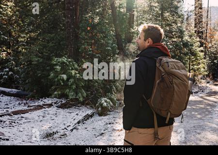 L'homme aime la randonnée dans la forêt enneigée tout en respirant l'air frais Banque D'Images