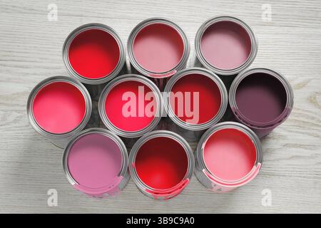Boîtes avec peinture dans les tons de rouge et rose sur fond de bois blanc, vue de dessus Banque D'Images