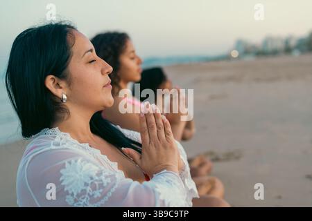 Groupe pratiquant la méditation consciente sur la plage Banque D'Images
