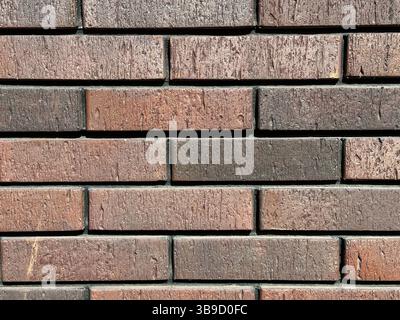 Gros plan d'un mur de briques présentant des surfaces texturées avec différentes nuances de rouge et de brun Banque D'Images