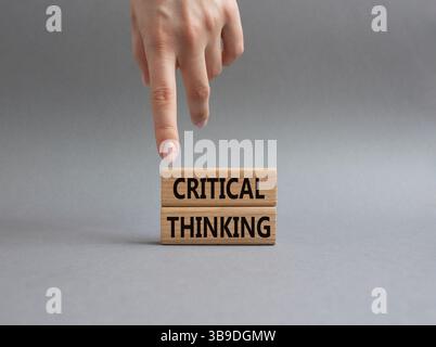 Symbole de pensée critique. Blocs en bois avec des mots pensée critique. Main d'homme d'affaires. Beau fond gris. Entreprise et pensée critique conc Banque D'Images