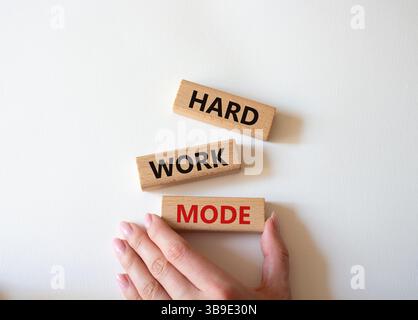Symbole du mode de travail acharné. Mot concept mode de travail dur sur des blocs de bois. Main d'homme d'affaires. Beau fond blanc. Concept de mode de travail professionnel et dur Banque D'Images