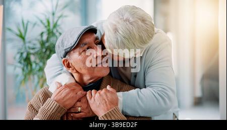 Couple senior, embrasser et embrasser dans les bras à la maison avec amour, lien et relation saine à la retraite. Homme âgé, femme mature et embrasser dans le salon Banque D'Images