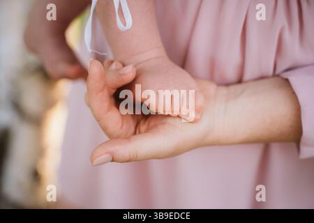 Moment tendre capturé par une mère tenant doucement le petit pied de son bébé. Le toucher doux transmet la chaleur, le soin et le lien spécial entre le parent et le chi Banque D'Images
