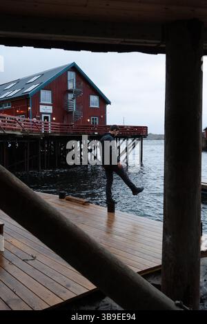 Homme explorant le village de pêcheurs rouge de Reine et Hamnoy dans les Lofoten, Norvège. Banque D'Images