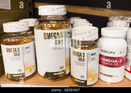 Minsk, Biélorussie - 28 avril 2025 : des bouteilles de compléments alimentaires Omega-3 Gold sont soigneusement disposées sur une étagère en bois dans un magasin. Banque D'Images