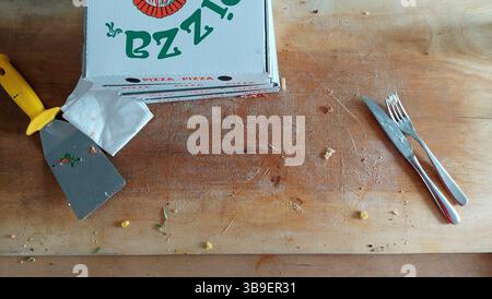 Planche de bois vide avec couteau et fourchette boîte à pizza après avoir mangé de la pizza Banque D'Images