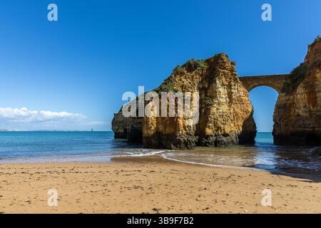 Une baie balnéaire sur laquelle le vieux pont de pierre du Fort Pinhao relie deux falaises. Praia da Caldeira, Lagos, Algarve, Portugal Banque D'Images
