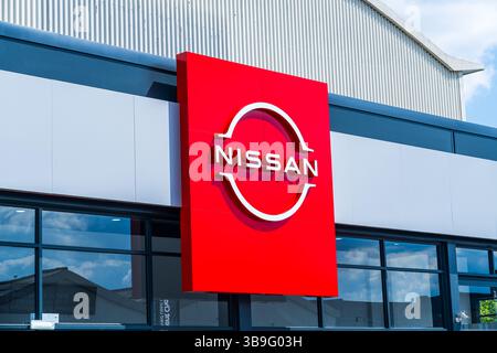 Wolverhampton, Royaume-Uni - 9 mai 2025 : signalisation externe du logo et du nom de la société Nissan Motor à l'extérieur d'une salle d'exposition d'un concessionnaire automobile Banque D'Images