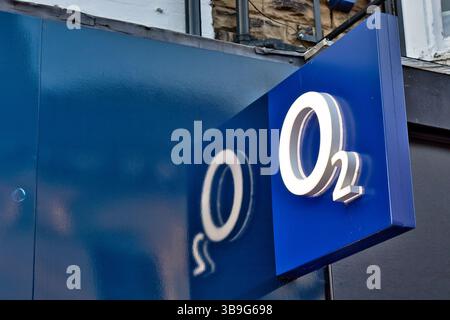 Gros plan d'un panneau bleu avec le logo O2 ; le logo est illuminé et projette une ombre sur la façade du bâtiment à Harrogate, Yorkshire, Royaume-Uni. Banque D'Images