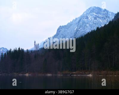 Majestueux château niché entre montagnes enneigées et lac serein dans un paysage hivernal Banque D'Images