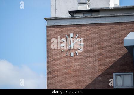 Horloge industrielle vintage extérieure avec chiffres romains sur un mur de briques d'un bâtiment industriel Banque D'Images