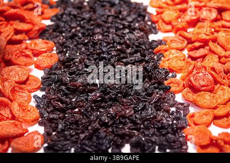 Abricots secs orange et raisins secs foncés isolés sur fond blanc vue de dessus. Fond de fruits séchés. Banque D'Images