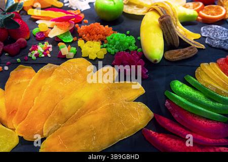 Divers fruits (kiwi, mangue, ananas, papaye, banane, orange, citron, pomme, melon, fruit de dragon) dans la vitrine de magasin de bonbons. Fruits secs backgrou Banque D'Images