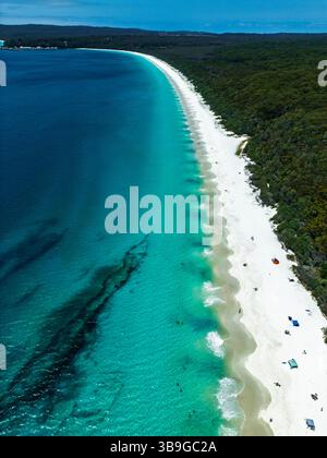 Vue aérienne d'une plage immaculée avec des eaux turquoises vibrantes et du sable blanc à Jervis Bay, en Australie. Une végétation dense borde le rivage. Escapade parfaite Banque D'Images