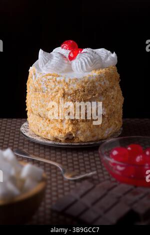 Une délicieuse costrada de Tudela, en Espagne, ornée de tourbillons de meringue et de cerises. Parfait pour les célébrations, ce gâteau repose sur une assiette à motifs, inv Banque D'Images