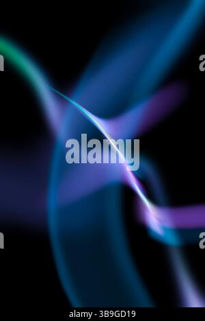 Image abstraite présentant des motifs lumineux ondulés et fluides en bleu et violet sur un fond sombre, créant une sensation de mouvement et une beauté éthérée. Banque D'Images