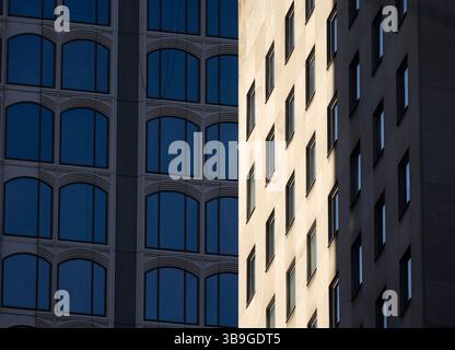 Styles architecturaux de deux bâtiments modernes adjacents à New York, capturant leurs façades uniques sous la lumière du soleil. Banque D'Images
