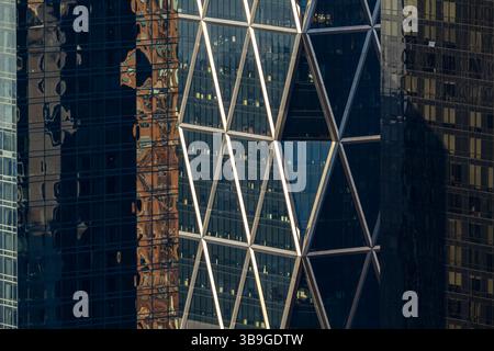 Gros plan du verre réfléchissant et de la structure en acier blanc d'un gratte-ciel moderne à New York, mettant en évidence les dessins géométriques et le textu urbain Banque D'Images