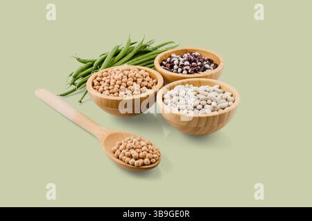 Les pois chiches, les haricots et les haricots verts sont présentés dans des bols en bois et une cuillère, soulignant leur valeur nutritive et leur contribution à une alimentation saine Banque D'Images