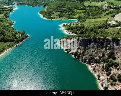 Vue aérienne sereine du Lago di Fiastra en Italie, mettant en valeur des eaux turquoises vibrantes encadrées par une végétation luxuriante et des falaises rocheuses, illustrant la nature Banque D'Images