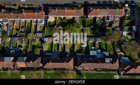 Vue aérienne des rangées de maisons avec des toits de tuiles rouges et des jardins verdoyants, divisés par des clôtures, par une journée ensoleillée, vue directement d'en haut à Morden, Londres, Banque D'Images