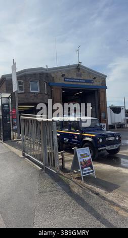 Seahouses Lifeboat Station avec véhicule stationné et panneau d'information. Bâtiment en pierre avec des accents bleus. Banque D'Images