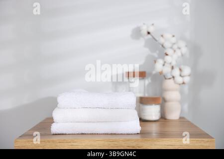 Pile de serviettes propres, fleurs de coton et tampons sur la table en bois à l'intérieur Banque D'Images