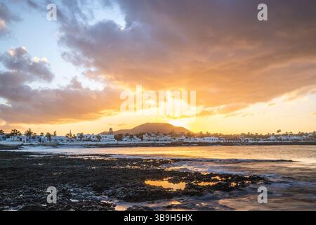 Coucher de soleil à Playa Vista Lobos, dans une longue exposition au bord de la mer, plage de lave avec vue sur la ville de Corralejo, Fuerteventura, îles Canaries, Espagne Banque D'Images