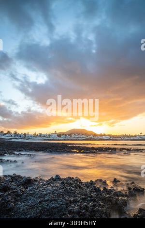 Coucher de soleil à Playa Vista Lobos, dans une longue exposition au bord de la mer, plage de lave avec vue sur la ville de Corralejo, Fuerteventura, îles Canaries, Espagne Banque D'Images