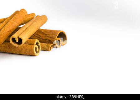Segments d'écorce de cannelle éparpillés sur blanc, mettant en valeur leur texture grossière, leurs tons bruns riches et leurs formes organiques, parfaits pour les pres culinaires et à base de plantes Banque D'Images