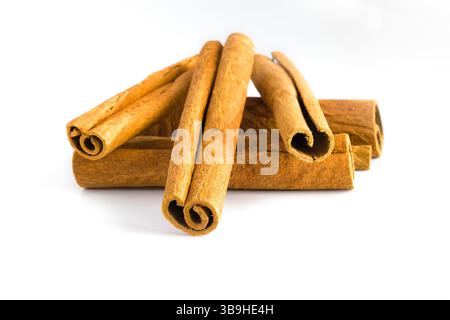 Gros plan de fragments d'écorce de cannelle séchée sur blanc, capturant leurs courbes naturelles, leurs surfaces rugueuses et leurs tons chauds, adaptés à la cuisine et aux wellnes Banque D'Images