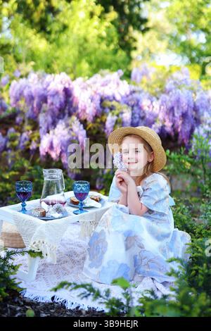Scène de pique-nique familiale extérieure avec fille joyeuse et cadre de table confortable dans la nature Banque D'Images