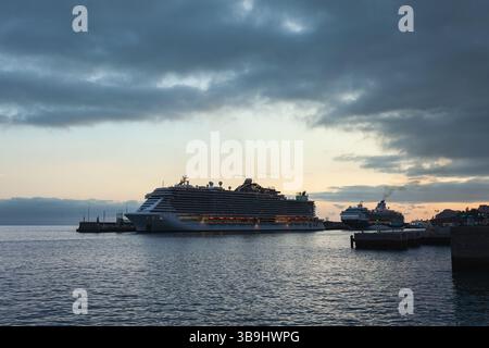 Vue au coucher du soleil sur la baie de Funchal à Madère, avec des bateaux de croisière faisant escale dans le port de Funchal lors de leurs traversées transatlantiques. Banque D'Images