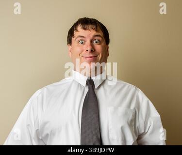 Un homme portant une chemise blanche et une cravate noire sourit et regarde la caméra Banque D'Images