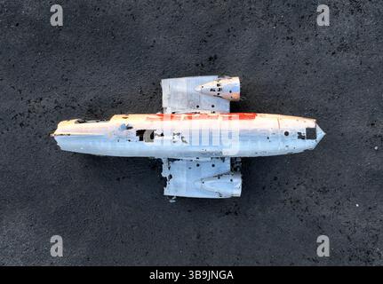 Vue aérienne montrant le fuselage altéré et les ailes de l'épave abandonnée de l'avion Sólheimajökull reposant sur le sable noir de l'Islande Banque D'Images