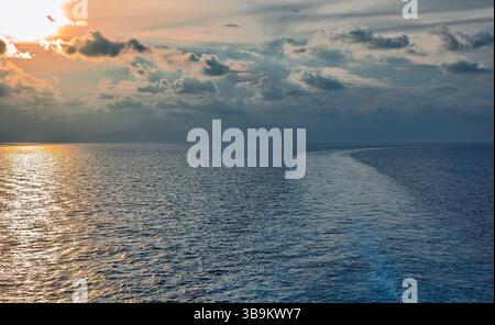 Lumière dorée sur l'océan au coucher ou au lever du soleil. Vue d'un bateau montrant le sillage de fuite. Représente le voyage, la paix, et la beauté de la mer et Banque D'Images