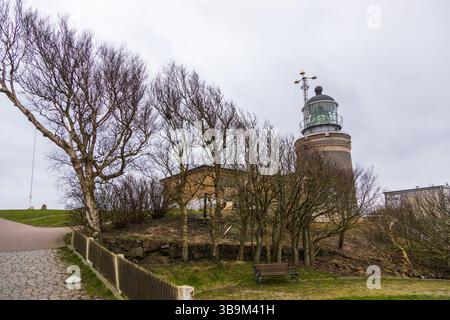 Vieux phare debout sur une falaise rocheuse au bord de la mer à Kullen, Suède. Jour de printemps couvert par la côte. Banque D'Images