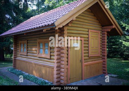 Une petite cabane en rondins avec un toit rouge et une garniture jaune. La porte est ouverte et il y a un panneau sur la porte qui dit '7' Banque D'Images