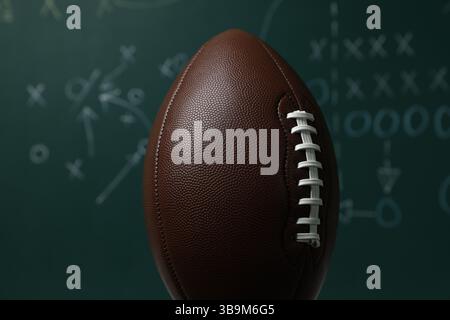 Ballon de football américain contre le schéma de jeu flou, gros plan Banque D'Images
