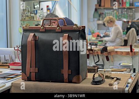 Artisanat artisanal fabriquant des articles en cuir sur mesure dans un atelier, démontrant les techniques traditionnelles de sellerie pour les accessoires de luxe Banque D'Images
