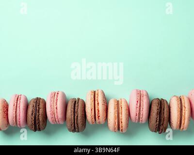 Macarons avec espace de copie. Rangée de macarons ou macarons français parfaits sur fond bleu turquoise. Vue de dessus ou plat Banque D'Images
