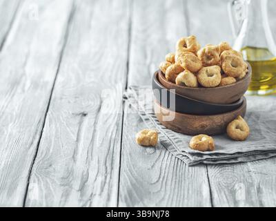 Taralli ou tarallini traditionnel italien snack dans un bol en bois sur une vieille table en bois gris. Plan rustique de taralli apéritif avec espace de copie Banque D'Images