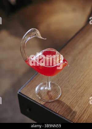 Cocktail cosmopolite en verre oiseau cygne, photo esthétique minimaliste sur le bord du comptoir du bar. Cocktail cosmopolite alcoolisé populaire à base de vodka, t Banque D'Images