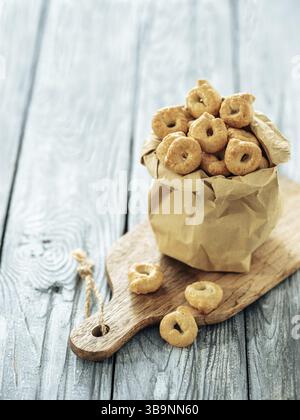 Taralli ou taralini italien traditionnel dans un sac en papier sur une ancienne table en bois grise. Photo rustique de taralli apéritif avec espace copie Banque D'Images