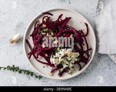 Salade spaghetti de betterave crue avec fromage à pâte molle, noix, thym.nouilles végétales - nouilles de betterave fraîches avec ricotta et thym frais sur l'assiette. Copier spac Banque D'Images