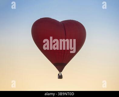 Montgolfière en forme de coeur rouge au fond de ciel de coucher de soleil. Vol en montgolfière en soirée avec une belle lumière du soleil. Romance de montgolfière en bon Wea Banque D'Images