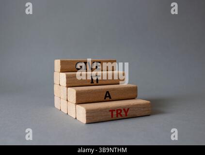 Donnez-lui un symbole essayer. Les mots conceptuels lui donnent un essai sur des blocs de bois. Beau fond gris. Et donnez-lui un concept d'essai. Copier l'espace. Banque D'Images