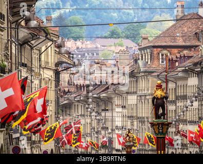 Berne, Suisse - 8 mai 2025 : une rue pittoresque de Berne, ornée de drapeaux cantonaux et suisses. Banque D'Images