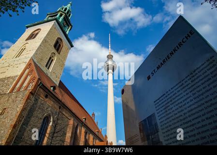 Panneau informatif devant l’église de Marie avec la tour de télévision emblématique de Berlin s’élevant en arrière-plan à Alexanderplatz. Banque D'Images